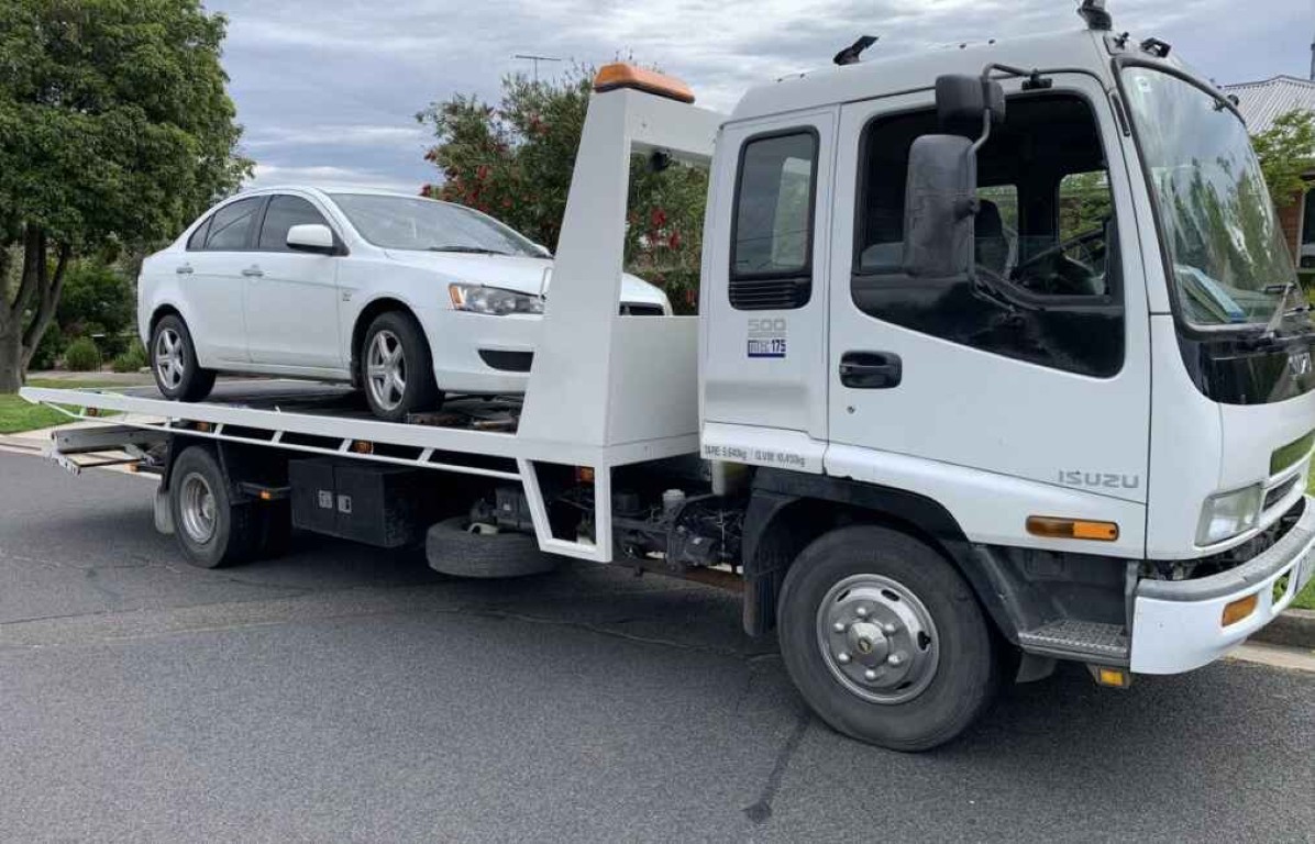 Professional towing team safely loading a white sedan in Erie, CO